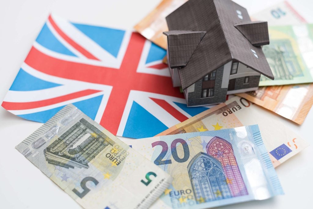 Model house placed on euro banknotes and a Union Jack flag, symbolising UK property investment.