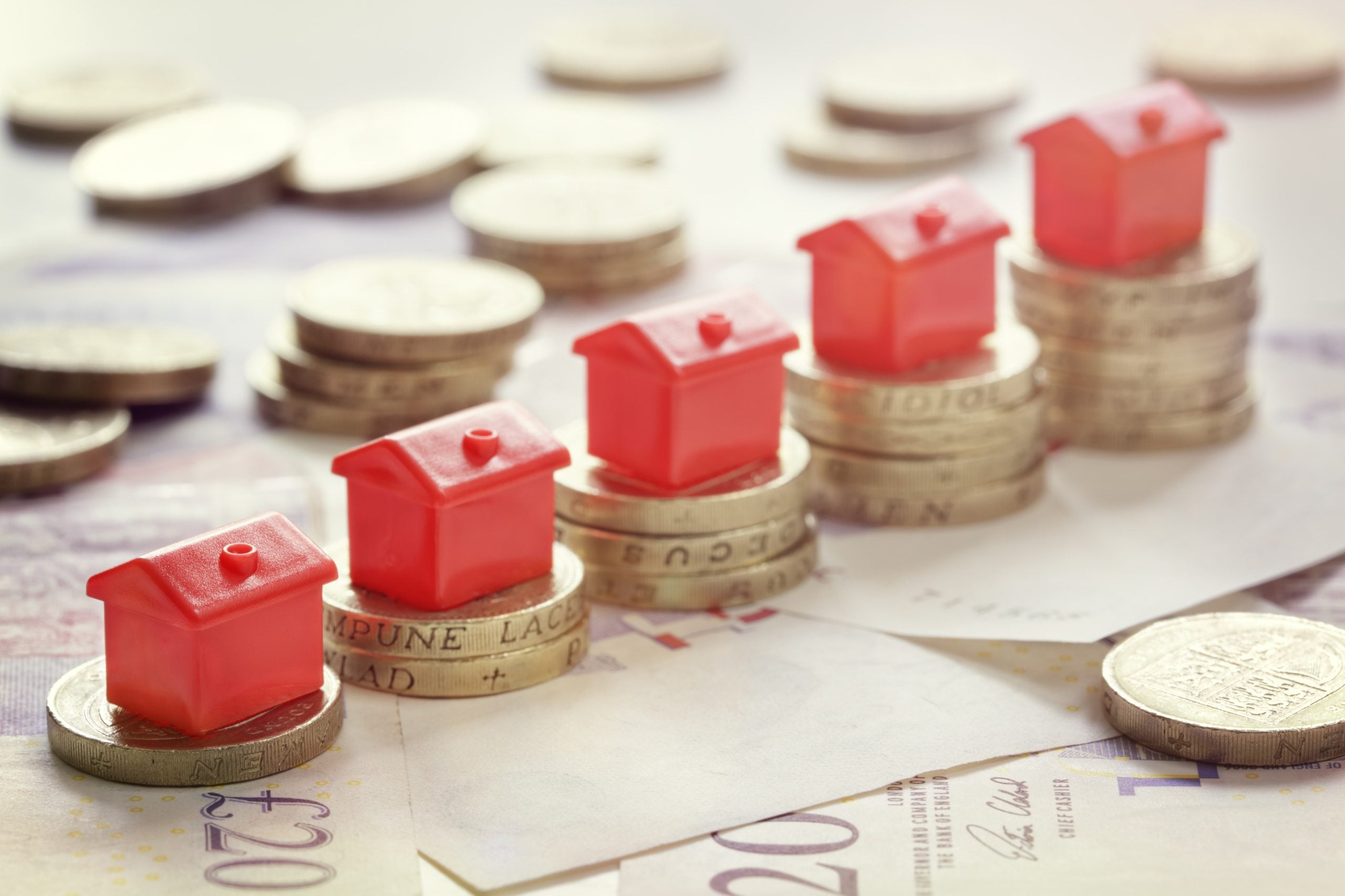 Red plastic houses on piles of pound coins showing buy-to-let returns.
